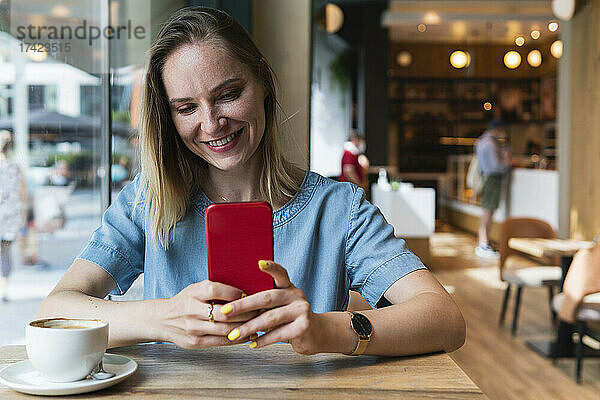 Freiberuflerin nutzt Smartphone  während sie im Café sitzt