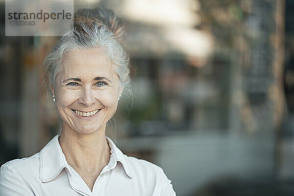 Lächelnde Frau mit grauem Haarknoten im Café