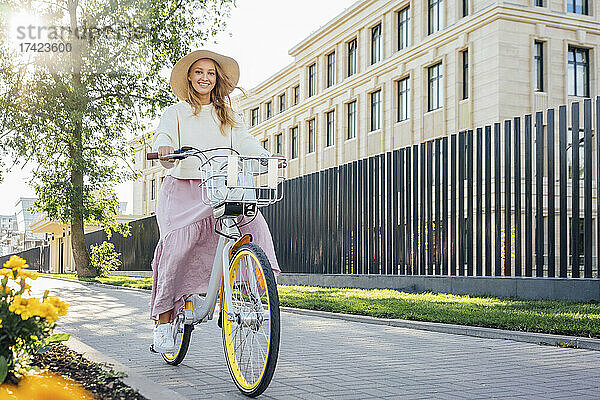 Lächelnde Frau fährt Fahrrad auf Fußweg
