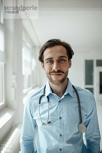 Lächelnder männlicher Arzt mit Stethoskop im Büro