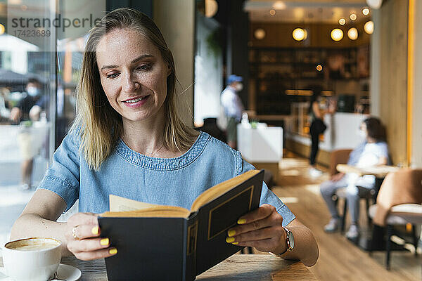 Blonde Geschäftsfrau liest Buch im Café