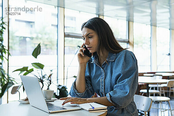 Geschäftsfrau arbeitet am Laptop und telefoniert im Café