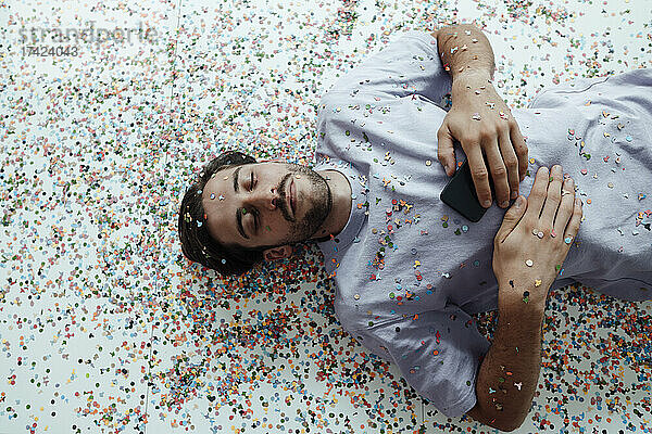 Young man relaxing on floor with confetti