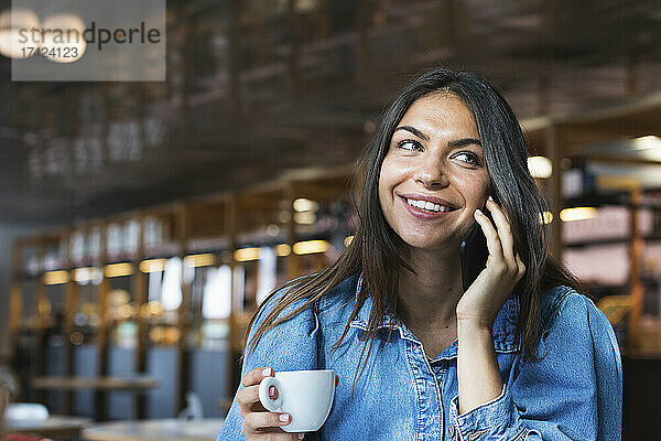 Lächelnde Freiberuflerin  die im Café mit dem Handy telefoniert