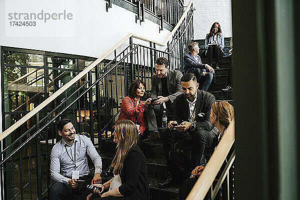 Geschäftsleute und Geschäftsfrauen diskutieren auf einer Treppe sitzend während einer Netzwerkveranstaltung