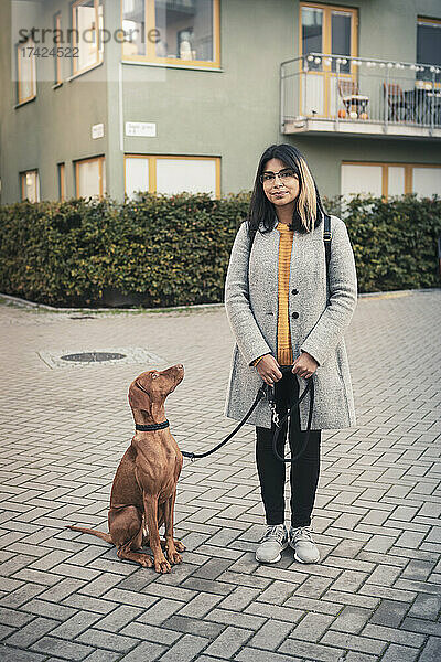 Porträt einer jungen Frau mit Hund auf einem Fußweg