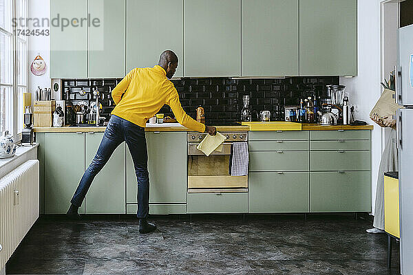 Voller Länge der Mitte erwachsenen Mann tut Hausarbeit in der Küche zu Hause