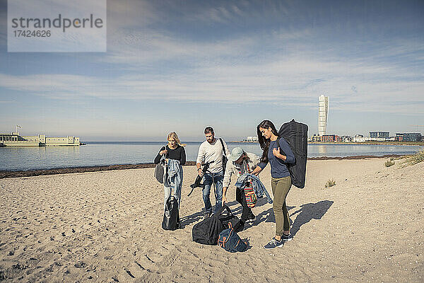 Männliche und weibliche Freunde mit Rucksäcken am Strand