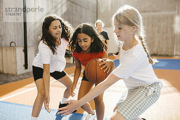 Freundinnen verteidigen sich beim Basketballspielen während eines Wettkampfs auf dem Platz