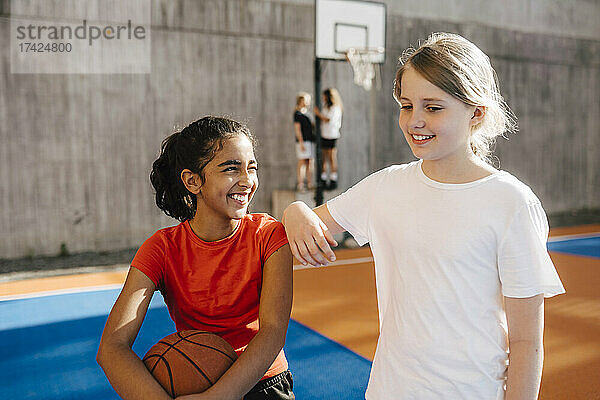 Lächelndes Mädchen  das eine Freundin auf dem Sportplatz ansieht