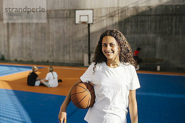 Lächelndes Mädchen mit Basketball auf dem Basketballplatz