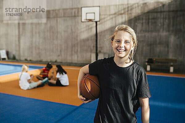 Porträt eines lächelnden Mädchens mit Basketball auf einem Sportplatz