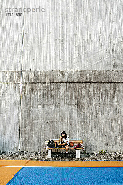 Vorpubertäres Mädchen sitzt auf einer Bank an der Wand