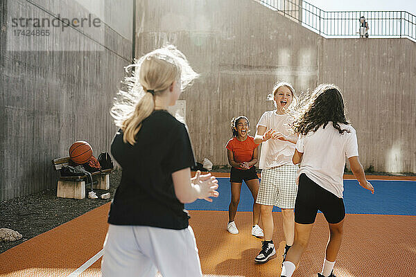 Fröhliche Freundinnen spielen auf dem Basketballplatz