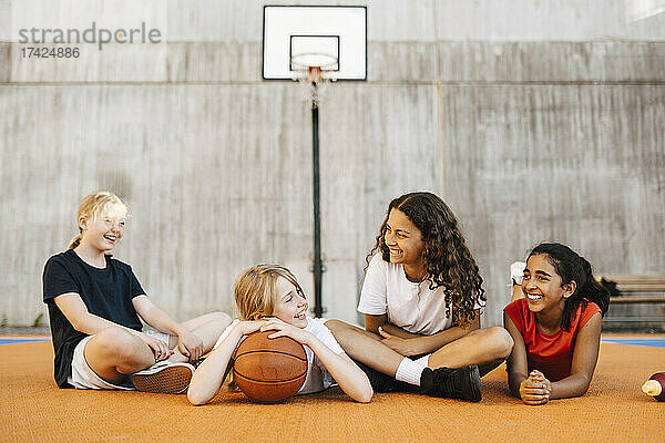 Lächelnde multiethnische Freundinnen verbringen ihre Freizeit auf dem Basketballplatz