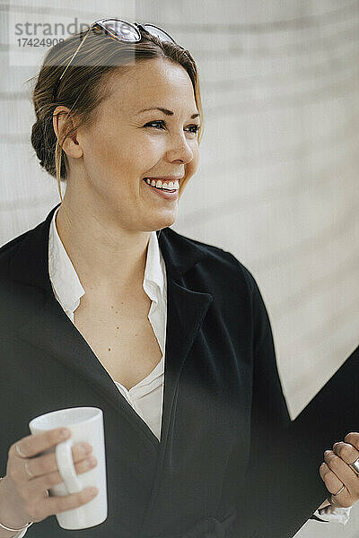 Glückliche Geschäftsfrau mit Kaffeebecher im Kongresszentrum