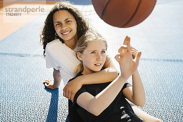 Porträt eines Mädchens  das mit einer Freundin auf einem Sportplatz sitzt