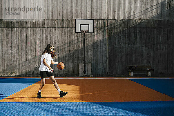 Eine Basketballspielerin dribbelt den Ball auf einem Sportplatz