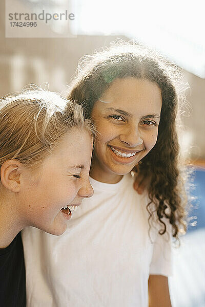 Porträt eines lachenden Mädchens mit Freundinnen auf dem Sportplatz