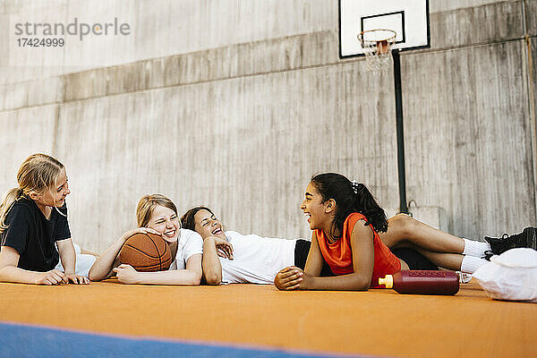 Fröhliche Mädchen lachen  während sie auf dem Sportplatz liegen