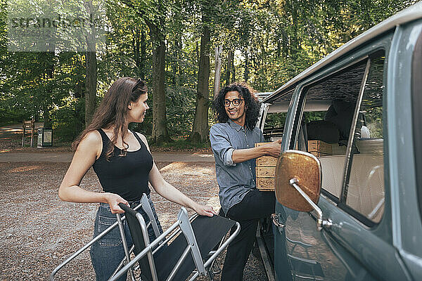 Männliche und weibliche Freunde entfernen Stuhl und Kiste aus dem Campingwagen
