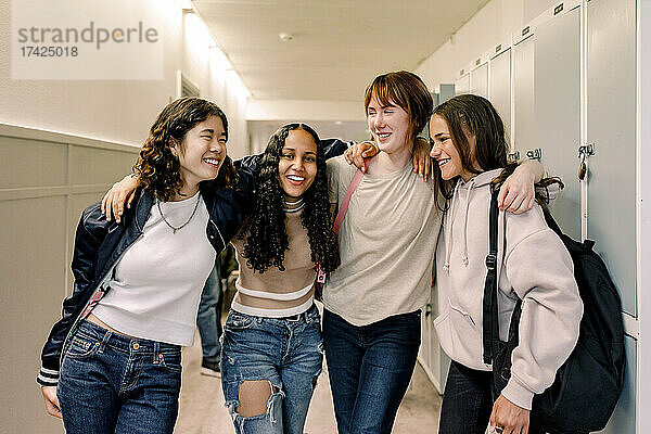 Lächelnde Freundinnen stehen zusammen im Korridor der Schule