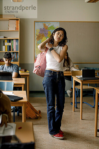 Teenager-Mädchen  das einen Rucksack trägt  während es im Klassenzimmer steht