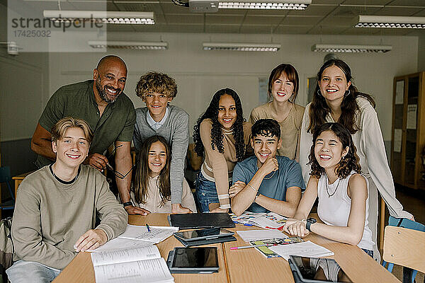 Porträt von lächelnden Teenager-Mädchen und Jungen mit männlichem Professor im Klassenzimmer