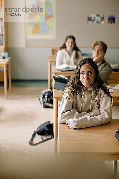 Lächelndes Teenager-Mädchen mit Freunden im Klassenzimmer