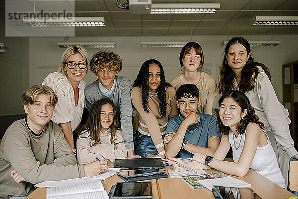 Porträt von lächelnden Teenager-Mädchen und Jungen mit Professorin im Klassenzimmer