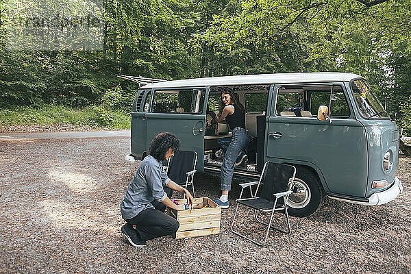 Junges Paar beim Ausladen des Gepäcks aus dem Van beim Camping