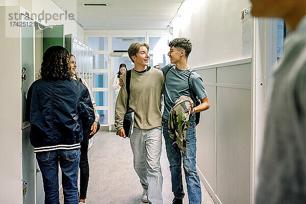 Lächelnde Teenager-Jungs gehen zusammen im Schulkorridor
