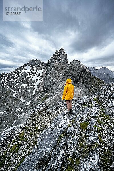 Wanderin blickt auf Berge bei dramatischen Wolken  Ausblick vom Gipfel der Westliche Törlspitze  hinten Partenkirchner Dreitorspitze  Wettersteingebirge  Garmisch-Partenkirchen  Bayern  Deutschland  Europa