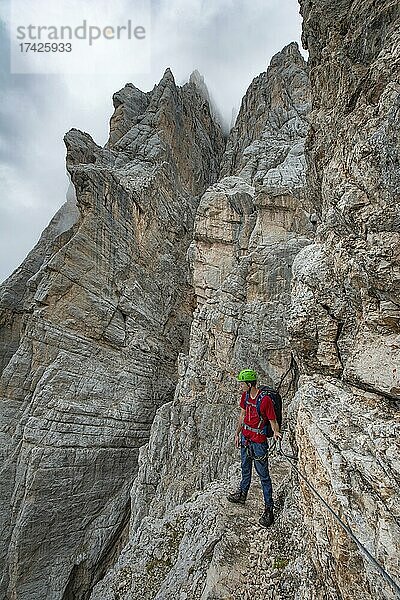 Junger Mann  Wanderer gesichert an einem Stahlseil beim Klettern an einer Felswand  Klettersteig Via Ferrata Francesco Berti  Sorapiss Umrundung  Dolomiten  Belluno  Italien  Europa