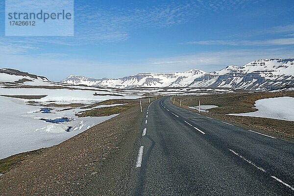 Straße führt durch karge Berglandschaft mit Schnee und Eis  Seydisfjördur  Fjarðarheiði  Island  Europa