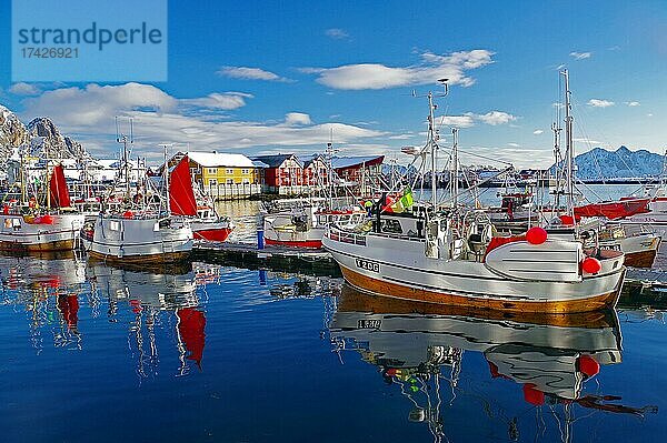 Fischerboote mit roten Segeln spiegeln sich im Wasser  Gebäude und Hotels im Hintergrund  Austvågøya  Svolvaer  Skandinavien  Norwegen  Europa