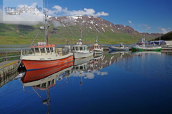 Kleine Fischerboote spiegeln sich im Hafenbecken  Berge und Schnee  Seydisfjördur  Ostisland  Island  Europa