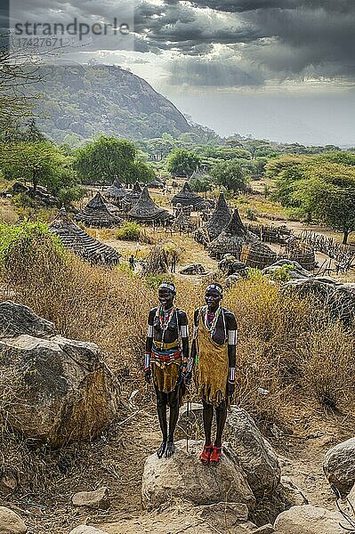 Traditionell gekleidete junge Mädchen vom Stamm der Laarim  die auf einem Felsen stehen  Boya Hills  Eastern Equatoria  Südsudan  Afrika