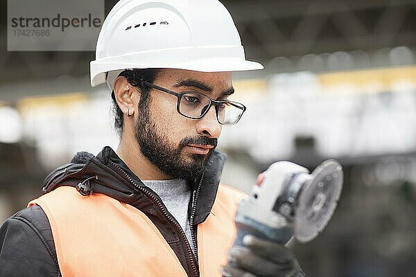 Techniker mit Bart und Helm arbeitet in einer Werkstätte  Freiburg  Baden-Württemberg  Deutschland  Europa