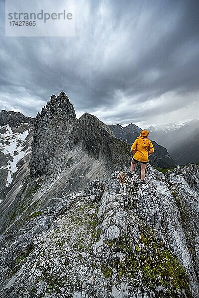 Wanderin blickt auf Berge bei dramatischen Wolken  Ausblick vom Gipfel der Westliche Törlspitze  hinten Partenkirchner Dreitorspitze  Wettersteingebirge  Garmisch-Partenkirchen  Bayern  Deutschland  Europa