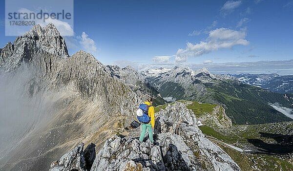 Wanderin auf einem Gipfel  Westliche Törlspitze  Berge bei dramatischen Wolken  mitte Zugspitze  hinten Patenkirchner Dreitorspitze  Wettersteingebirge  Garmisch-Partenkirchen  Bayern  Deutschland  Europa