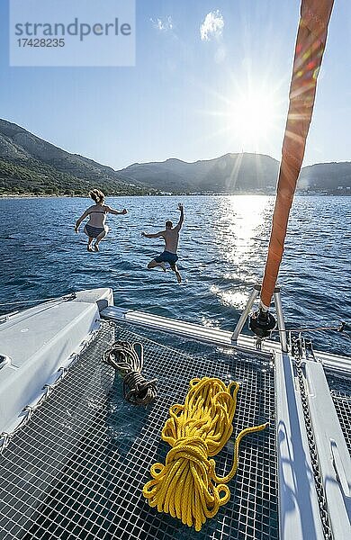 Junge Frau und junger Mann springen ins Wasser  Seile auf einem Segel-Katamaran  Sonnenstern  Segeltörn  Tilos  Dodekanes  Griechenland  Europa