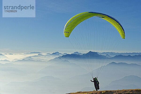 Startender Gleitschirmflieger mit den Gipfel der Gardasee Berge und Bergamasker Alpen  Monte Baldo  Malcesine  Verona Italien  Trentino-Alto Adige  Italien  Europa