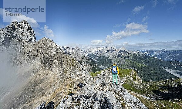 Wanderin auf einem Gipfel  Westliche Törlspitze  Berge bei dramatischen Wolken  mitte Zugspitze  hinten Patenkirchner Dreitorspitze  Wettersteingebirge  Garmisch-Partenkirchen  Bayern  Deutschland  Europa