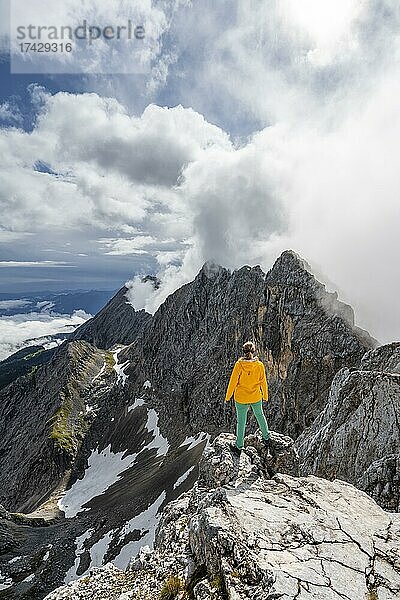 Wanderin auf einem Gipfel  Westliche Törlspitze  Berge bei dramatischen Wolken  Wettersteingebirge  Garmisch-Partenkirchen  Bayern  Deutschland  Europa