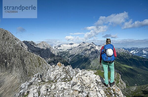 Wanderin auf einem Gipfel  Westliche Törlspitze  Berge bei dramatischen Wolken  mitte Zugspitze  Wettersteingebirge  Garmisch-Partenkirchen  Bayern  Deutschland  Europa