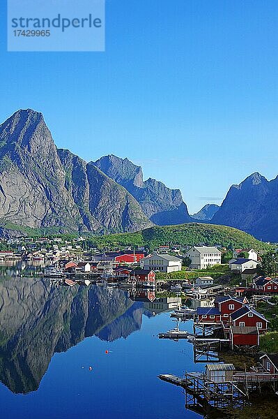 Holzhäuser und schroffe Berge spiegeln sich perfekt im Wasser  Reine  Reinefjord  Moskenes  Lofoten  Nordland  Norwegen  Europa