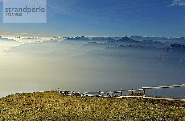 Wiese mit Zaun und Gardasee im Morgennebel mit Gardasee Berge und Bergamasker Alpen  Monte Baldo  Malcesine  Verona Italien  Trentino-Alto Adige  Italien  Europa