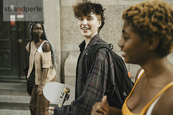 Porträt eines lächelnden Teenagers  der mit jungen Freunden in der Stadt spazieren geht