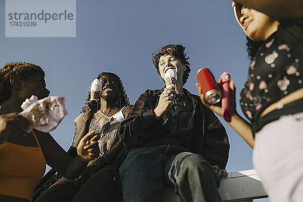 Lächelnde multirassische Freunde mit Eis am sonnigen Tag